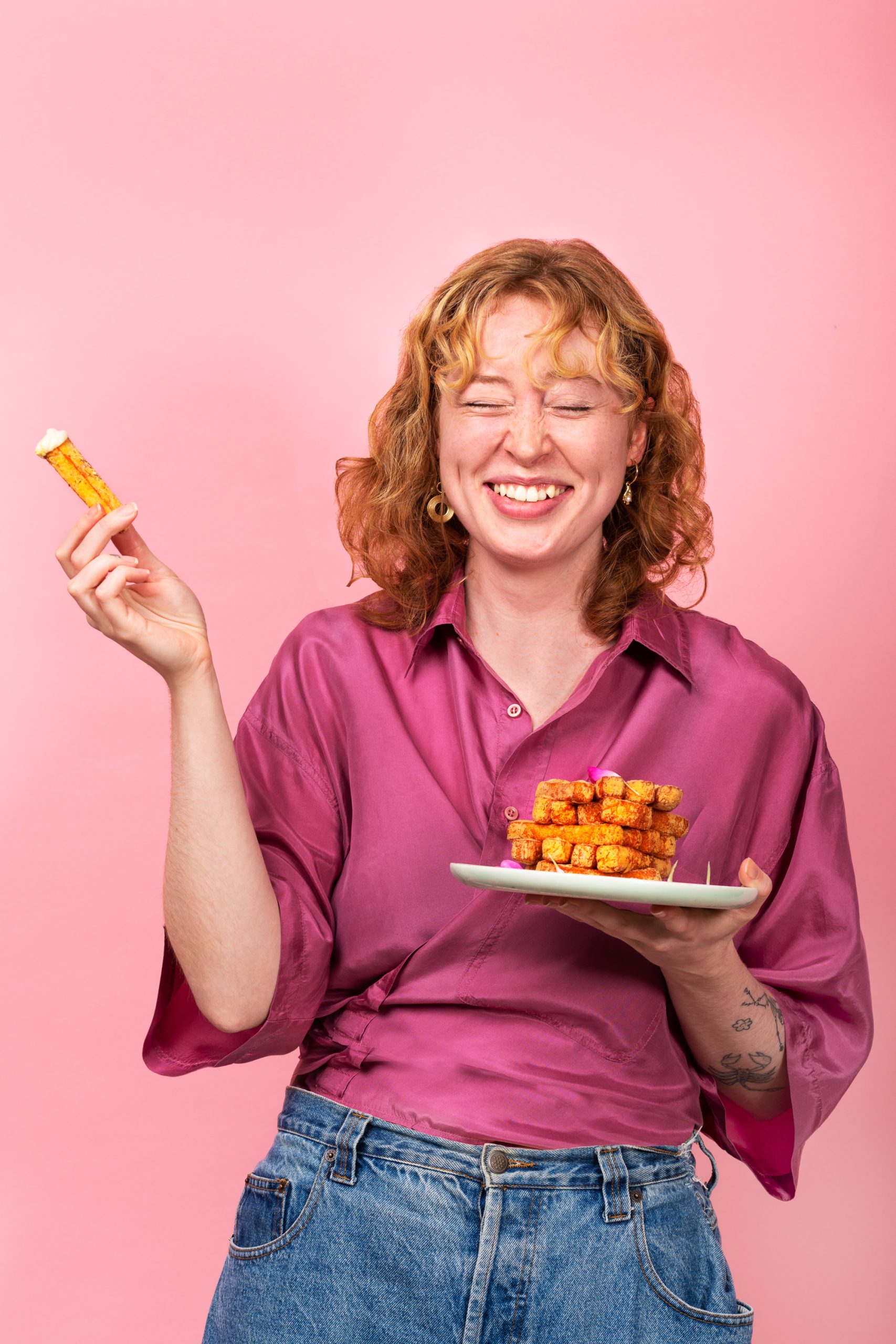 A person laughing while eating halloumi fries.